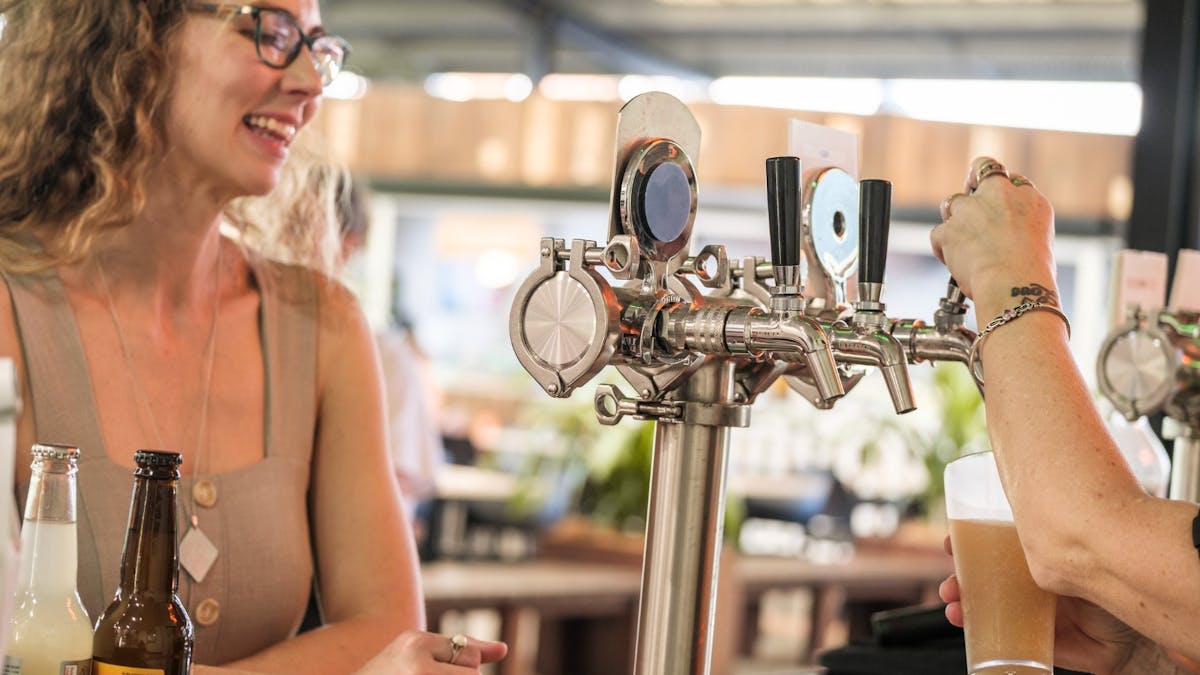 Woman waiting for ginger beer to be poured from beer tap