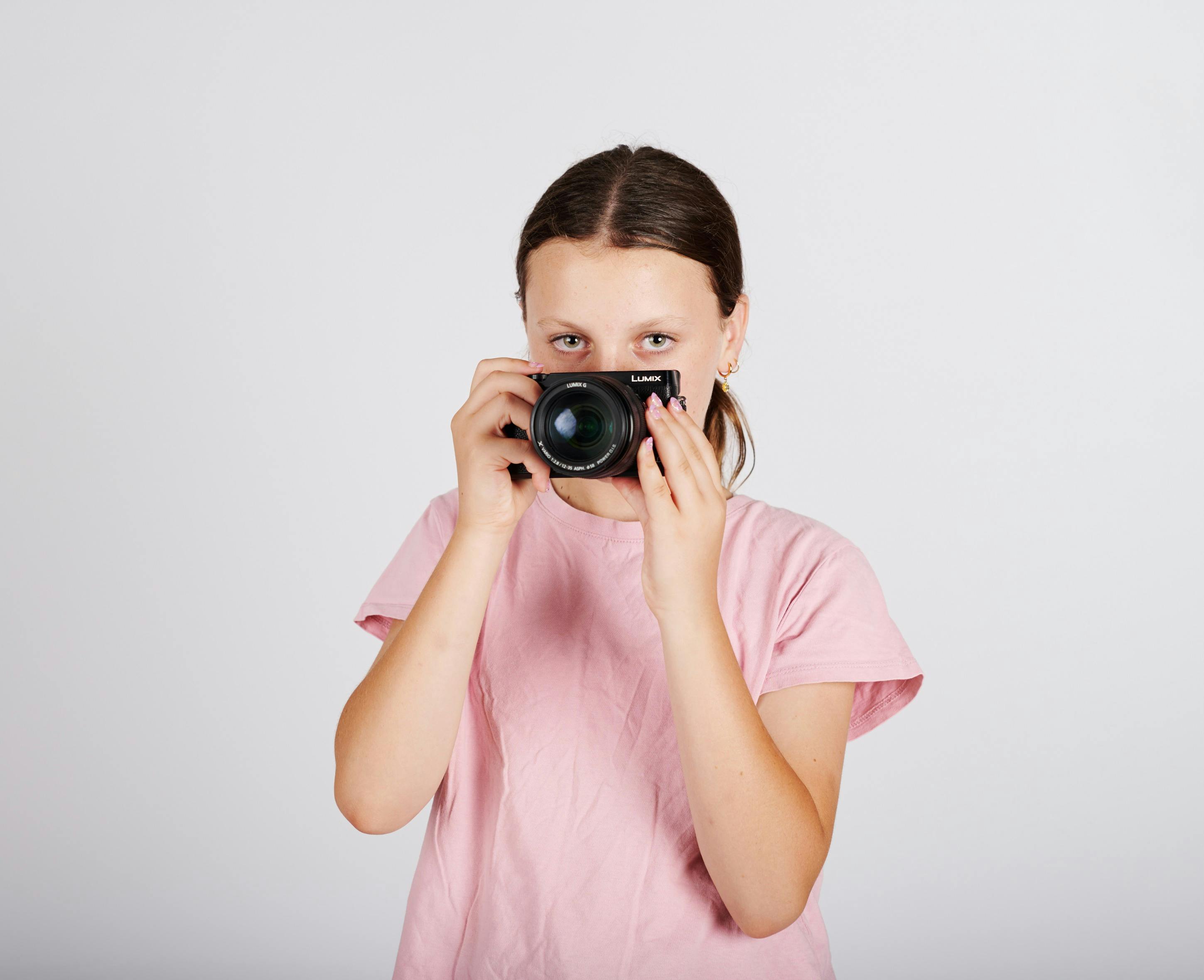 a teenaged girl holds a camera in front of her face