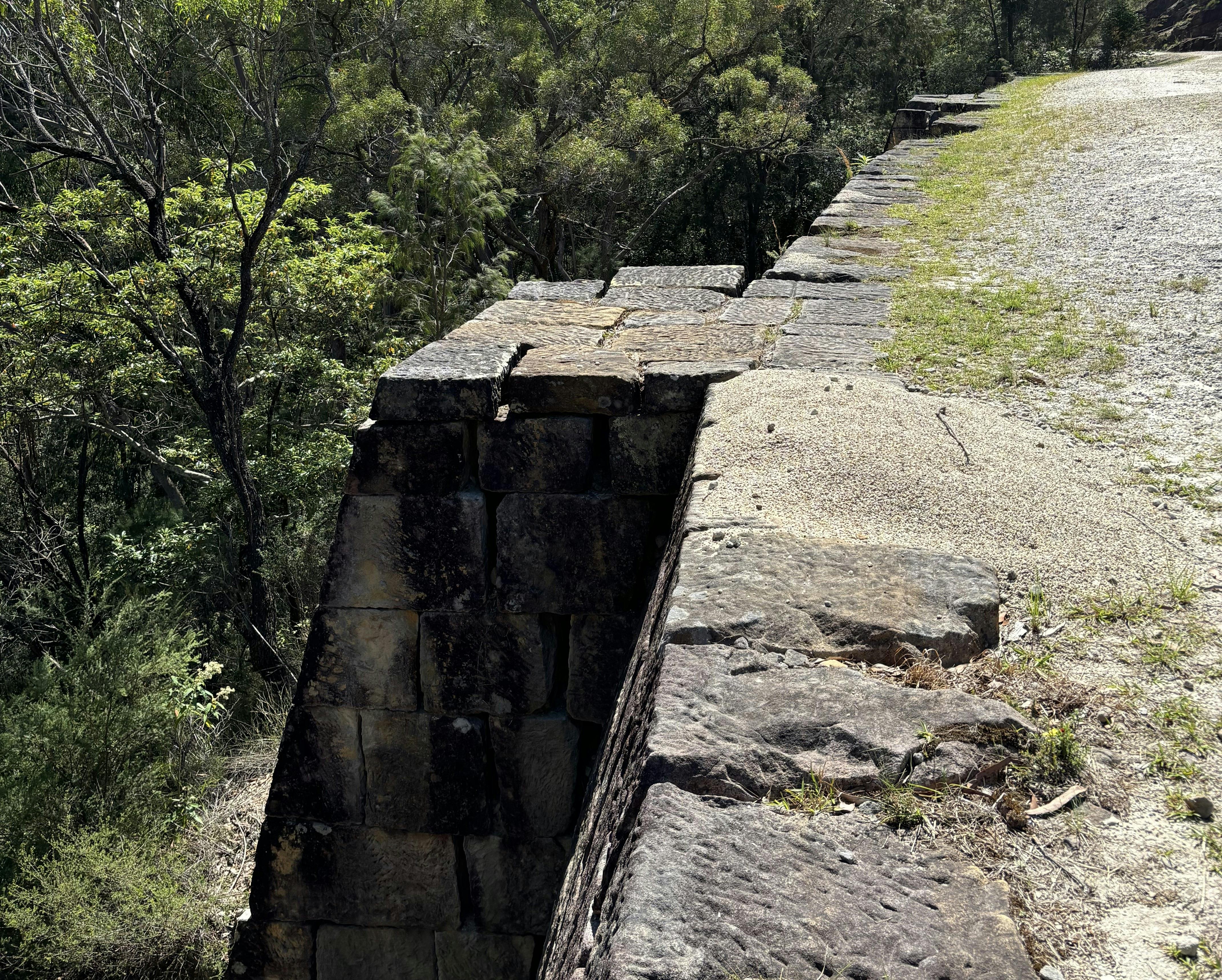 A large stone wall on the edge of a cliff supporting a convict built road.