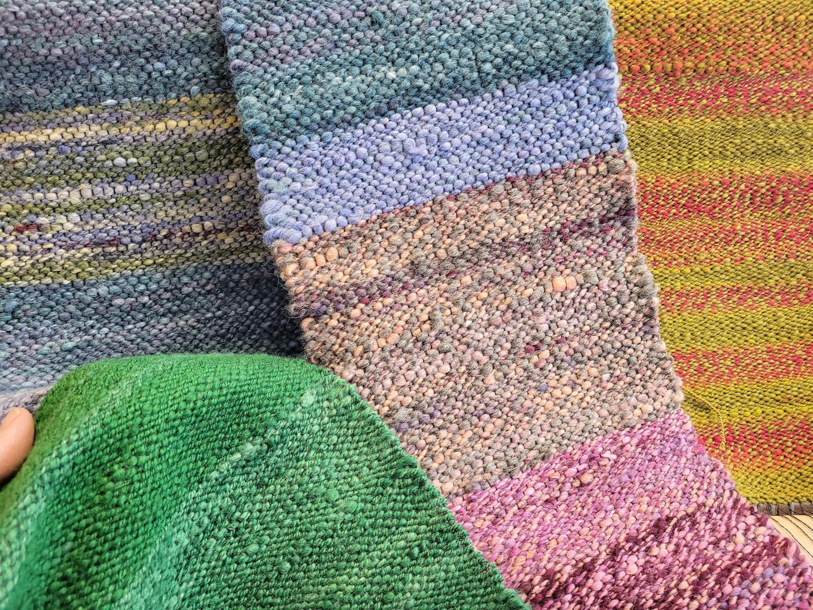 Hand woven scarves in bright colours are draped together.