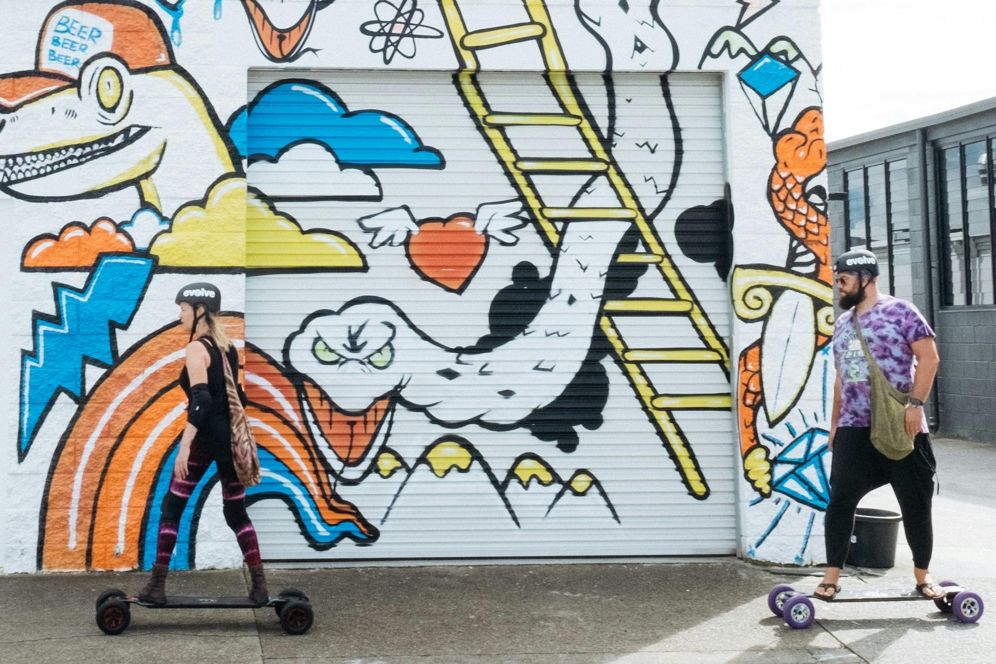 Skaters rolling past the Precinct mural