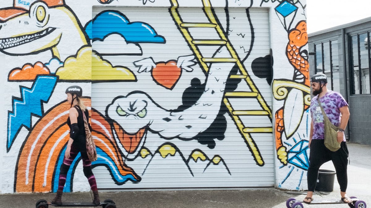 Skaters rolling past the Precinct mural