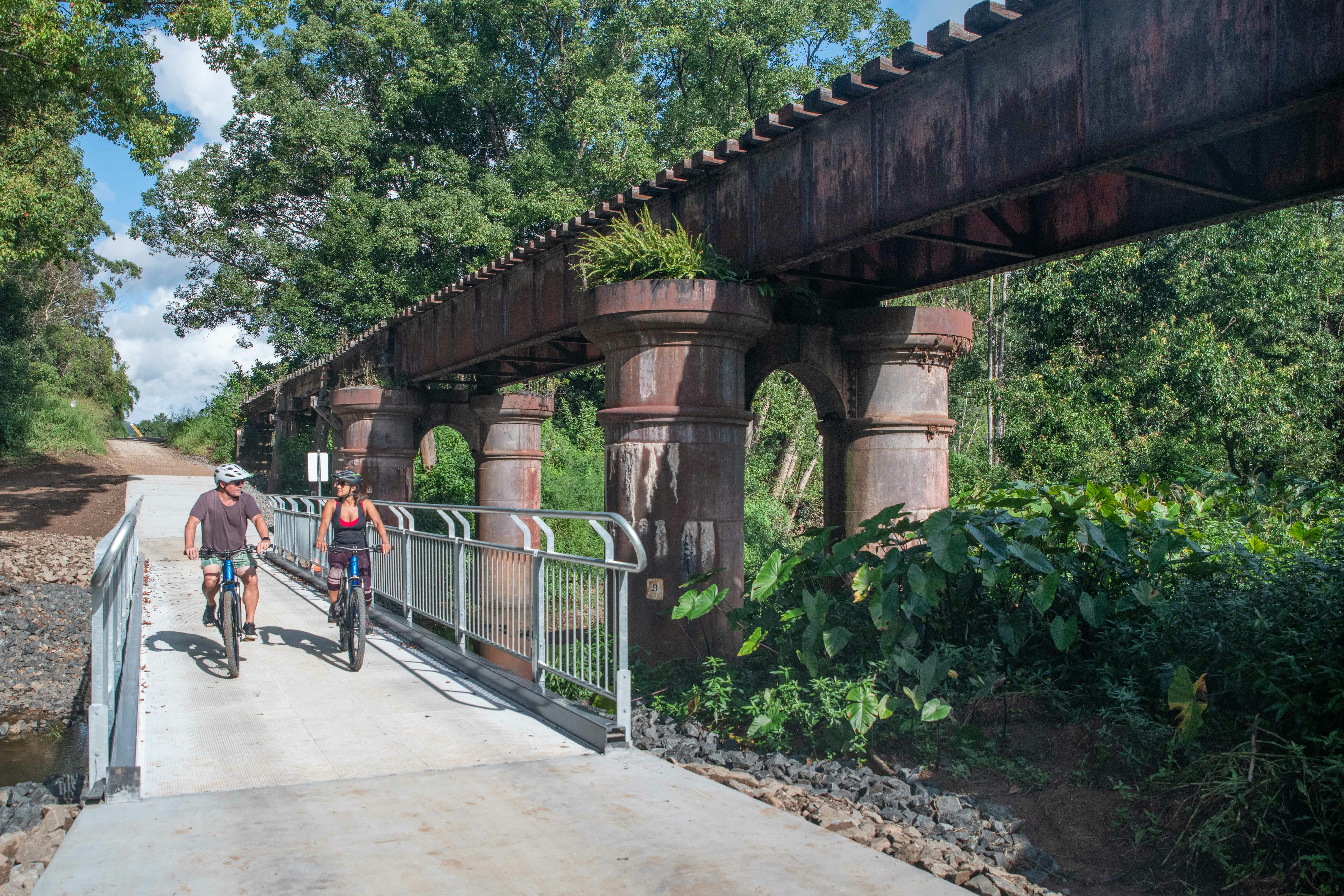 Two riders on ebikes in front of railway tunnel