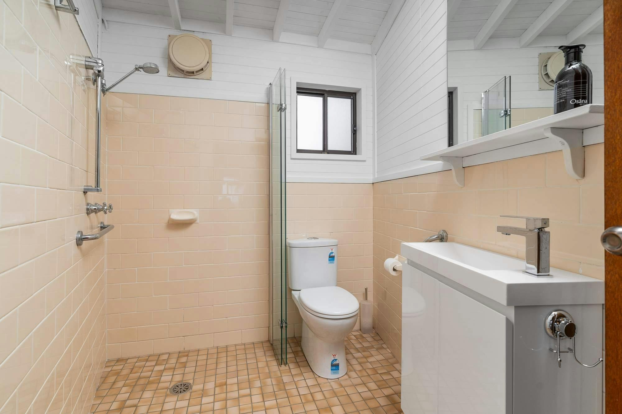 복숭아색 타일 샤워기 변기 세면대가 있는 욕실