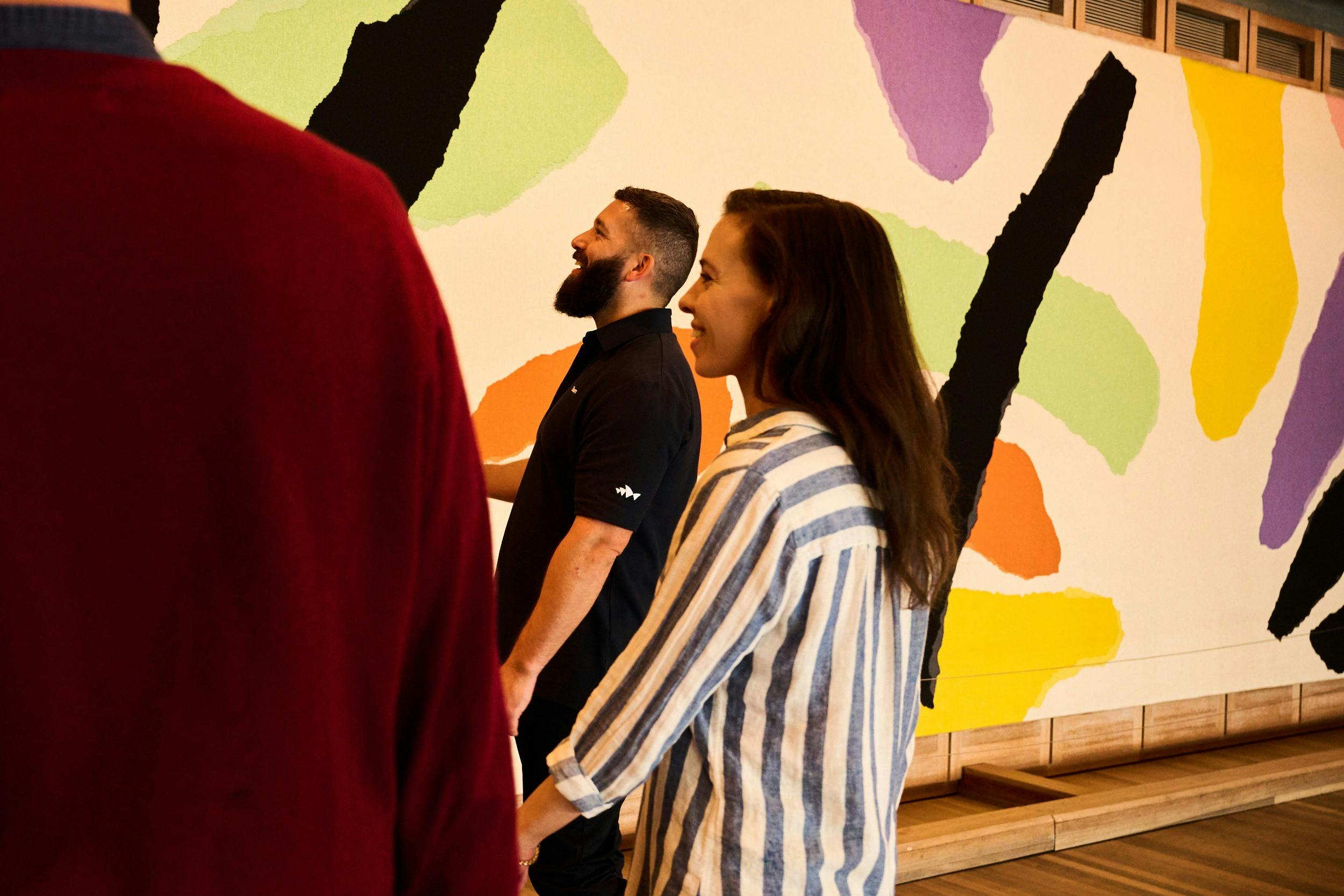 Utzon 태피스트리 앞에 서 있는 투어 가이드와 여성