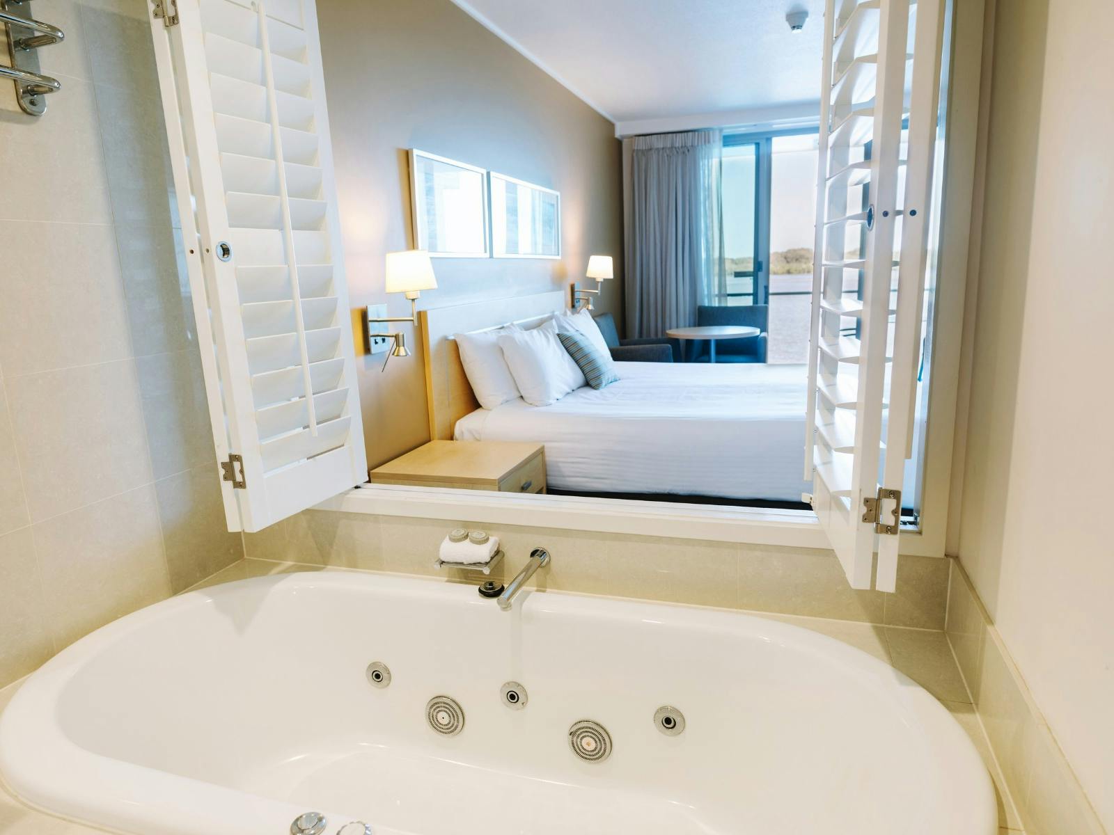 A Spa Bath with shutters opening to a bedroom with balcony waterviews.