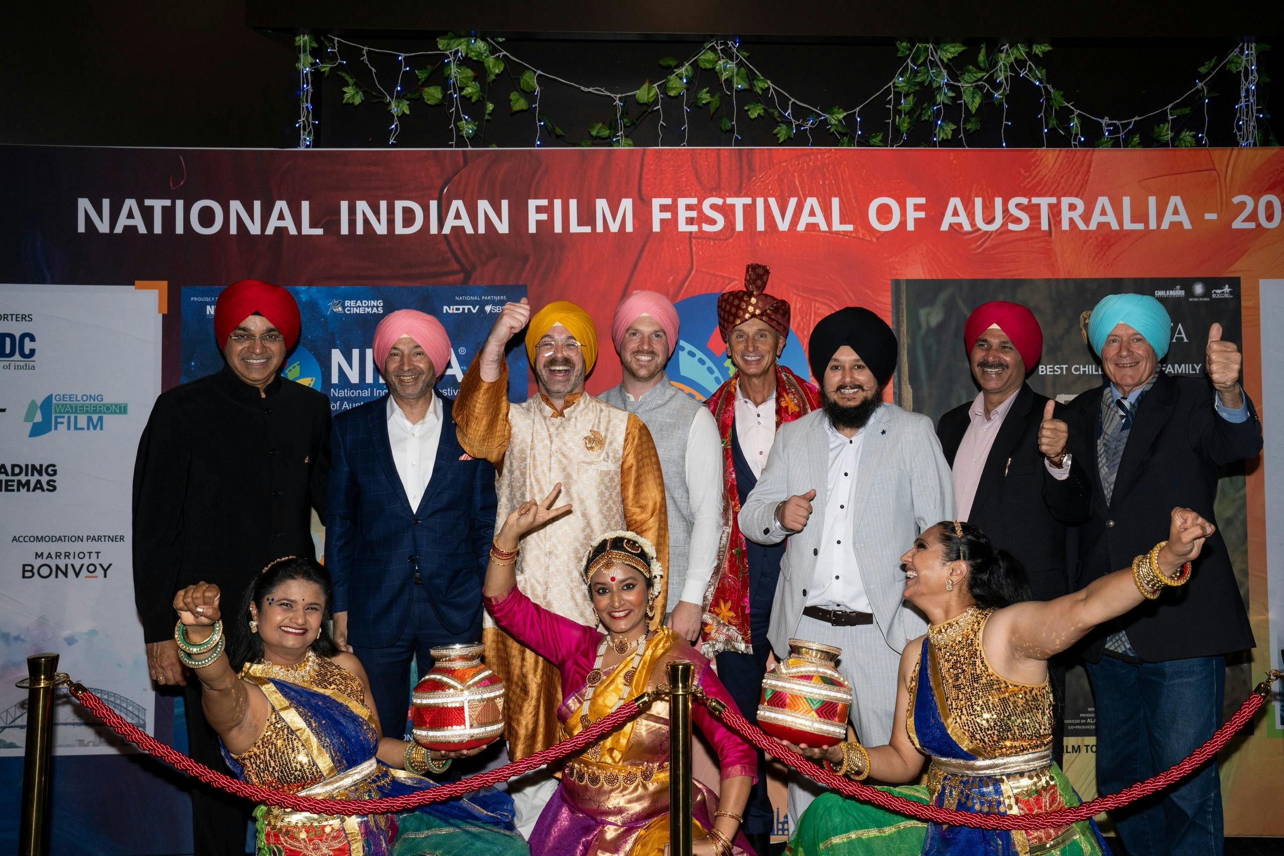 A group photo of NIFFA team and guests in front of the media wall at the opening night event