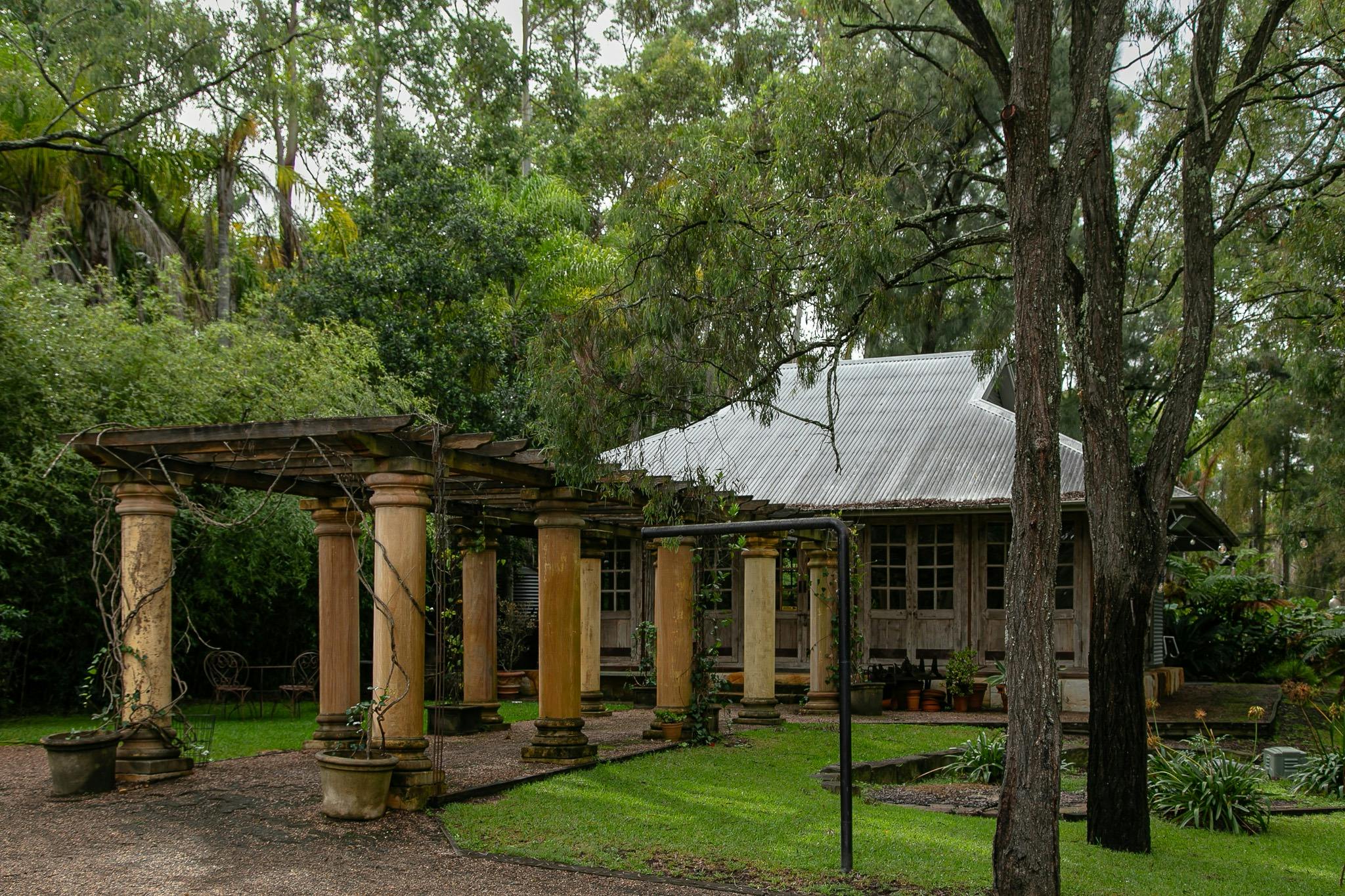 a timber building with a colonnade in front surrounded by lush greenery