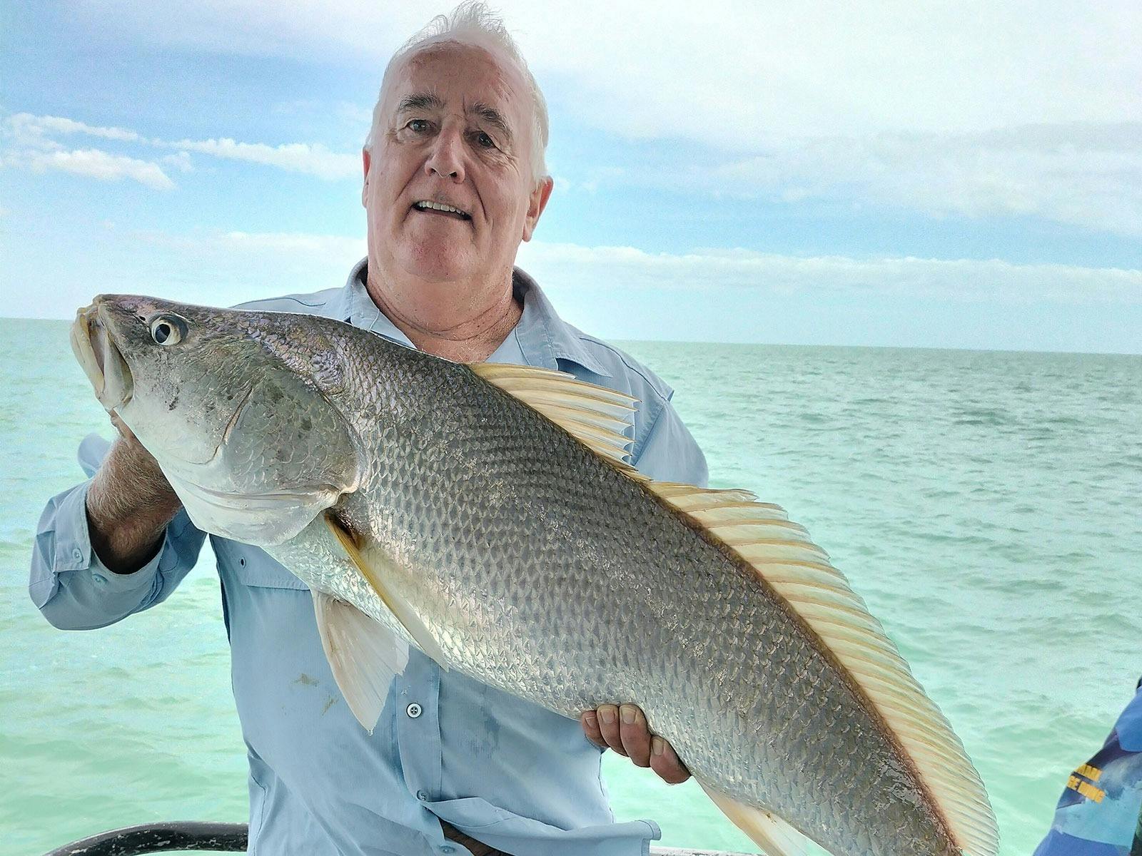 A man holding a fish on a Darwin Red Devil Charter.