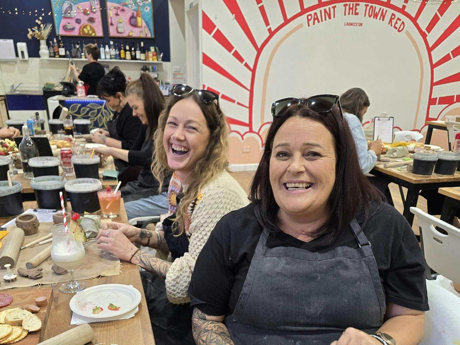 Two women enjoying a pottery class and cheeseboard