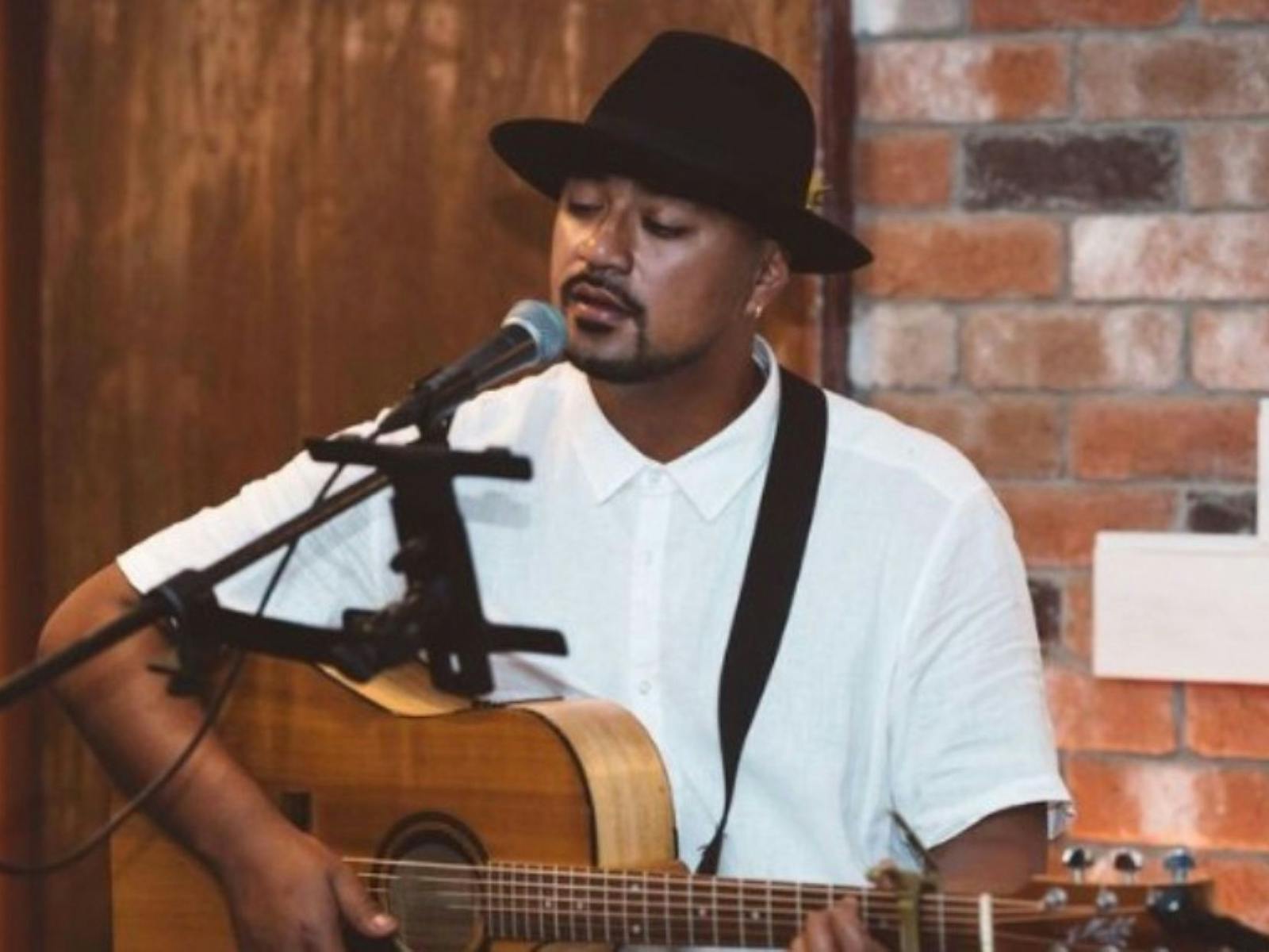 Image of a guitarist singing into a microphone