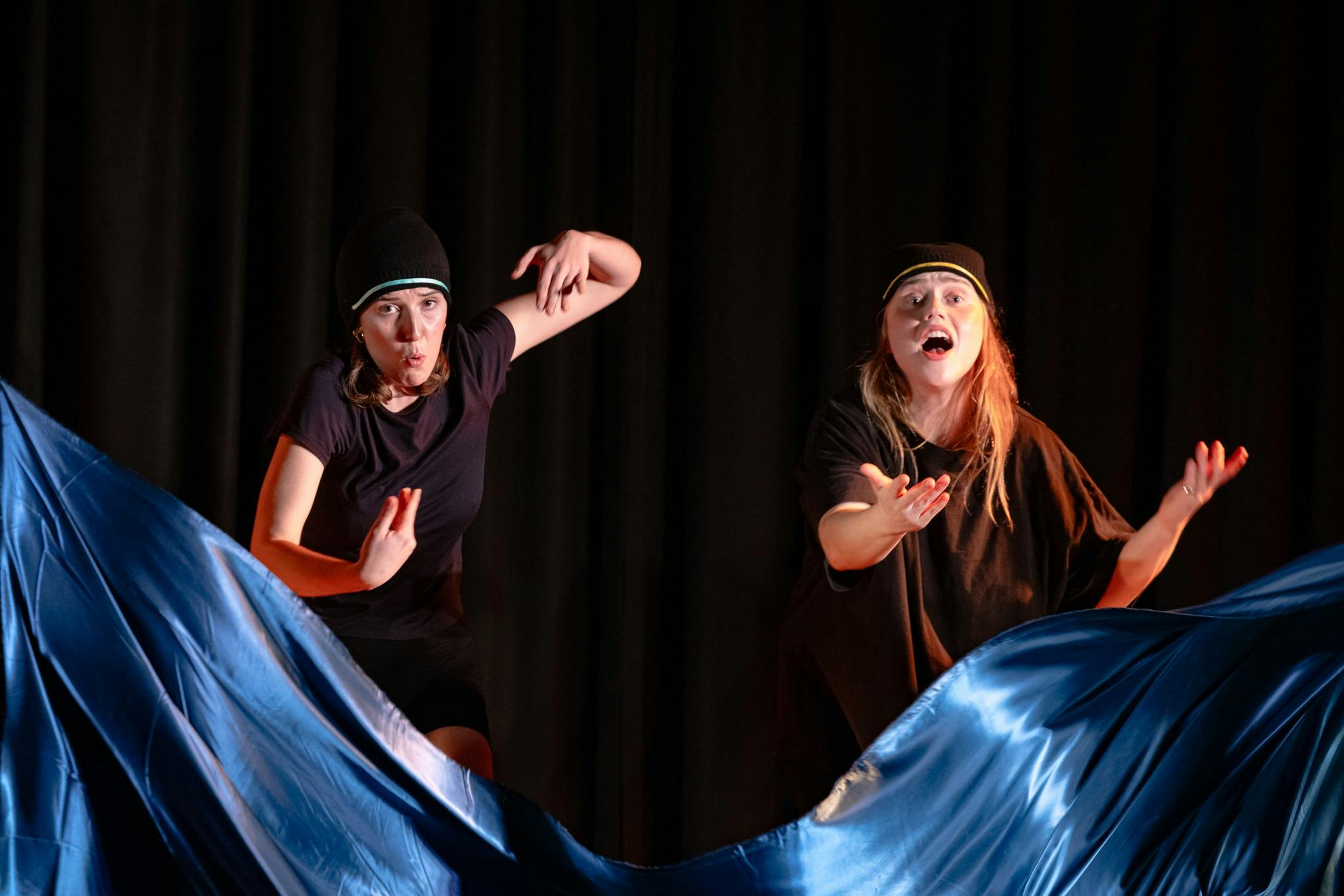 Two women behind a blue silk cloth pretending to swim