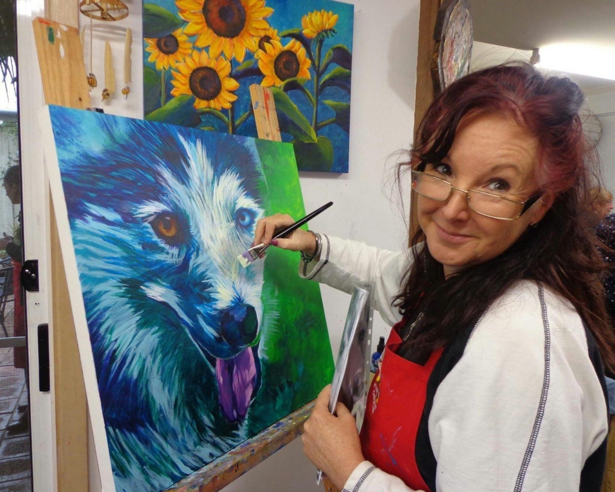 Woman artist painting a dog on canvas