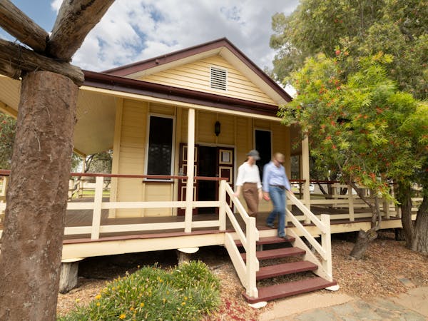 Two people walking down the front steps of an old wooden building Two people walking down the front steps of an old wooden building