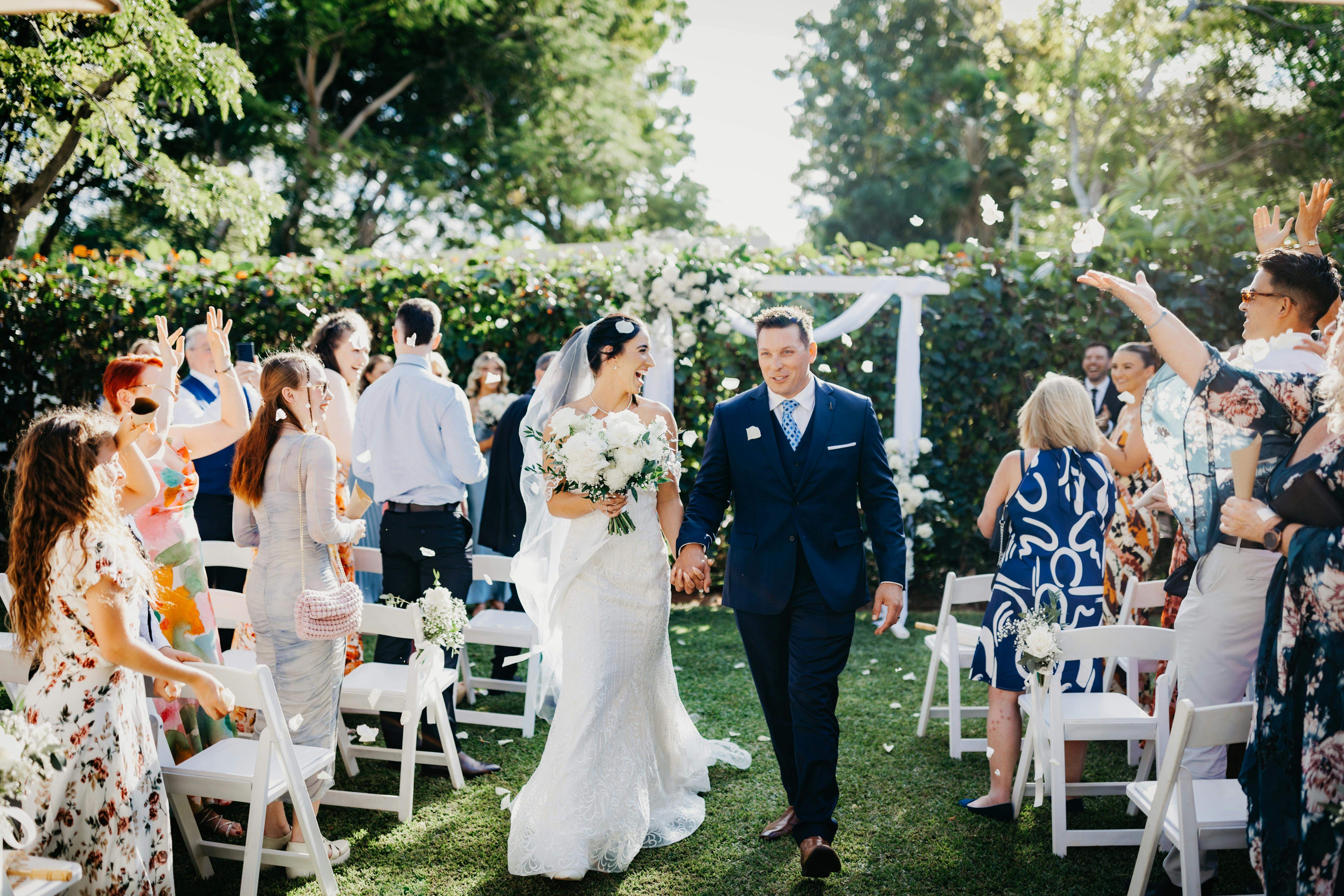 The happy couple walks the aisle as newlyweds, surrounded by cheers and flower petals.