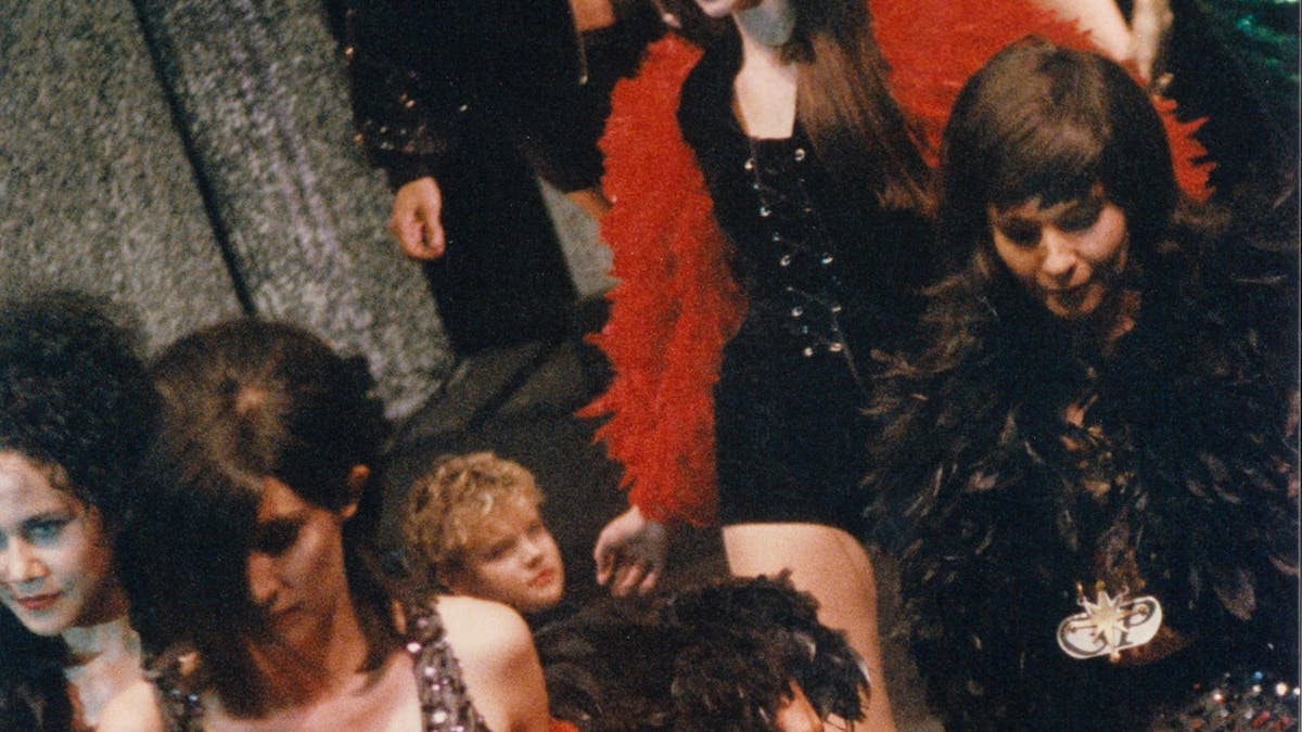 Models wearing black and red walk in a fashion parade.