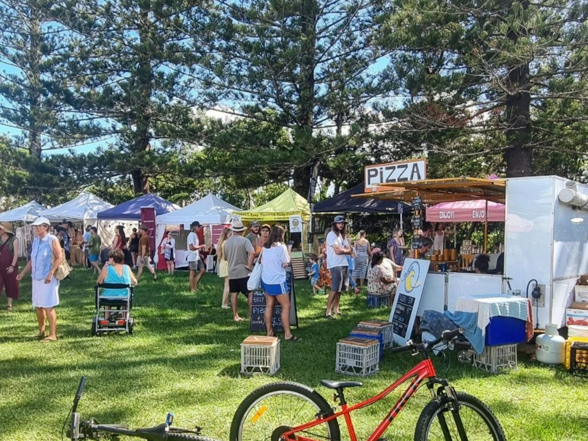 Wide shot of the market stalls and patrons gathered under the trees
