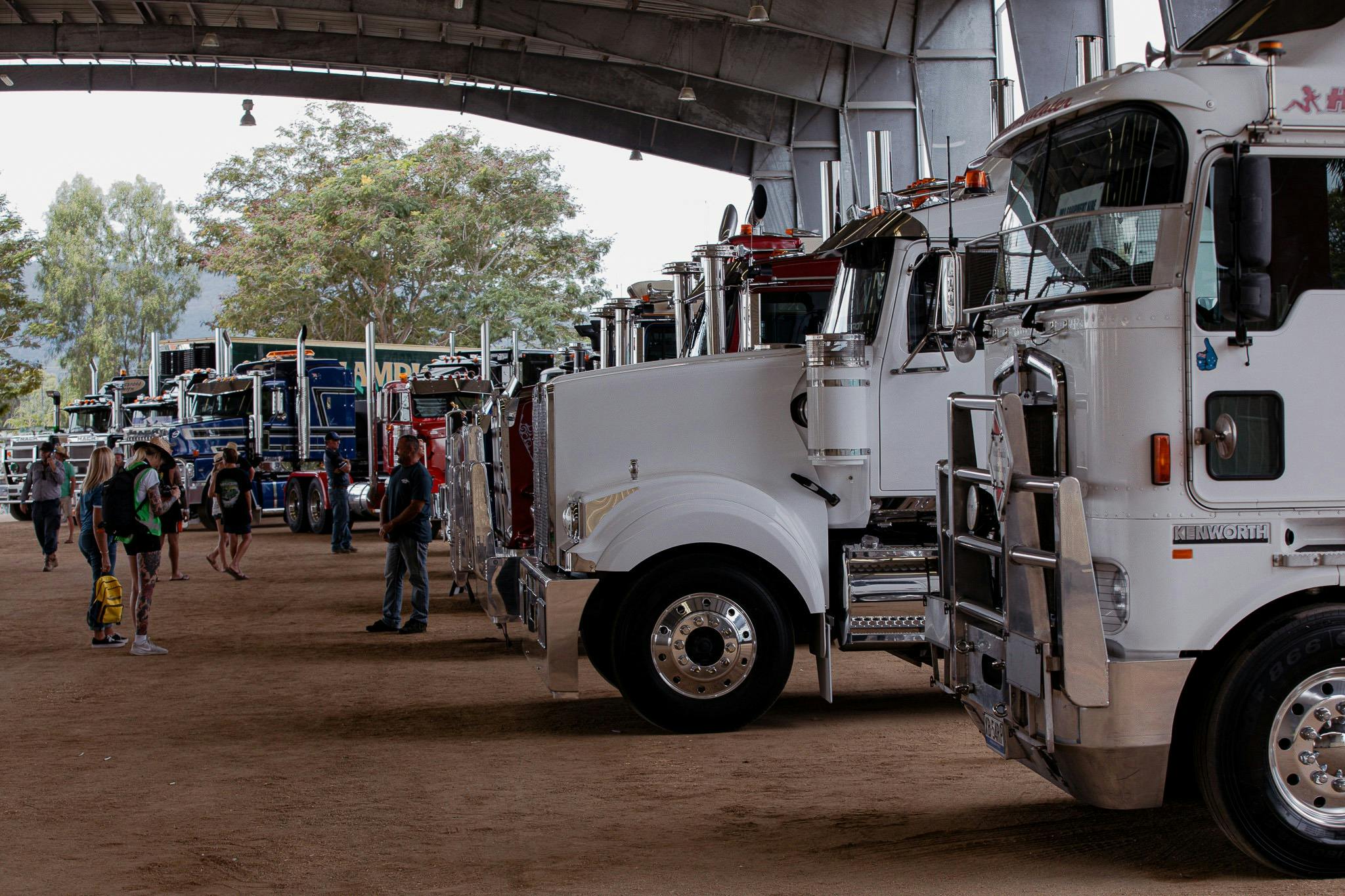 Custom trucks lined up on display inside a large shed at Rockynats.