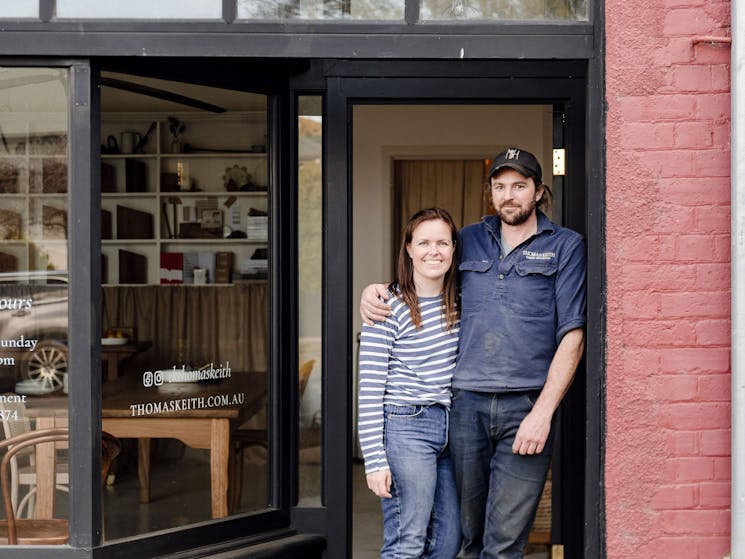 Husband and wife, craftsman and designer, standing out the front of their studio showroom.