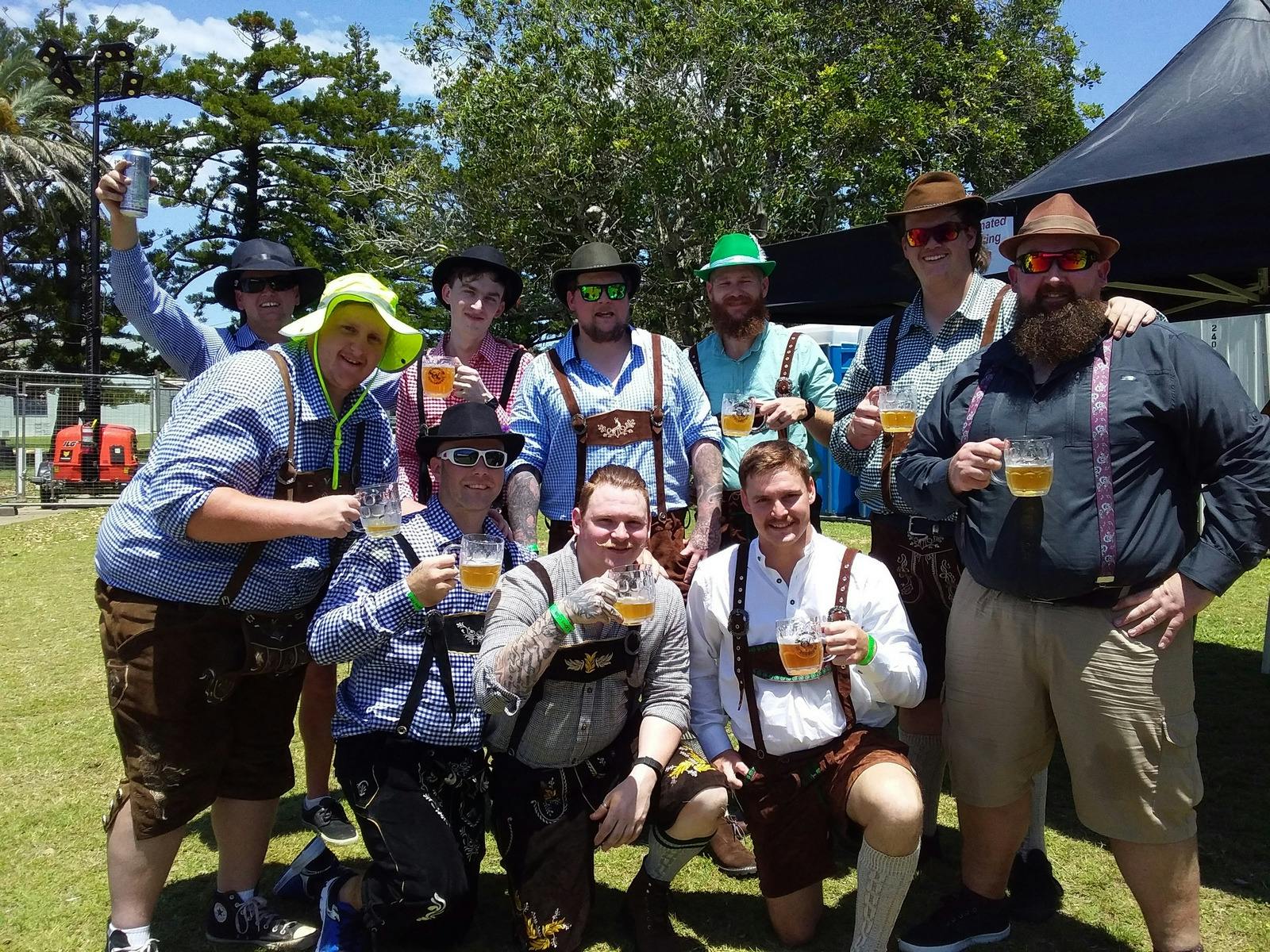 Guys in Oktoberfest dress with their beers.