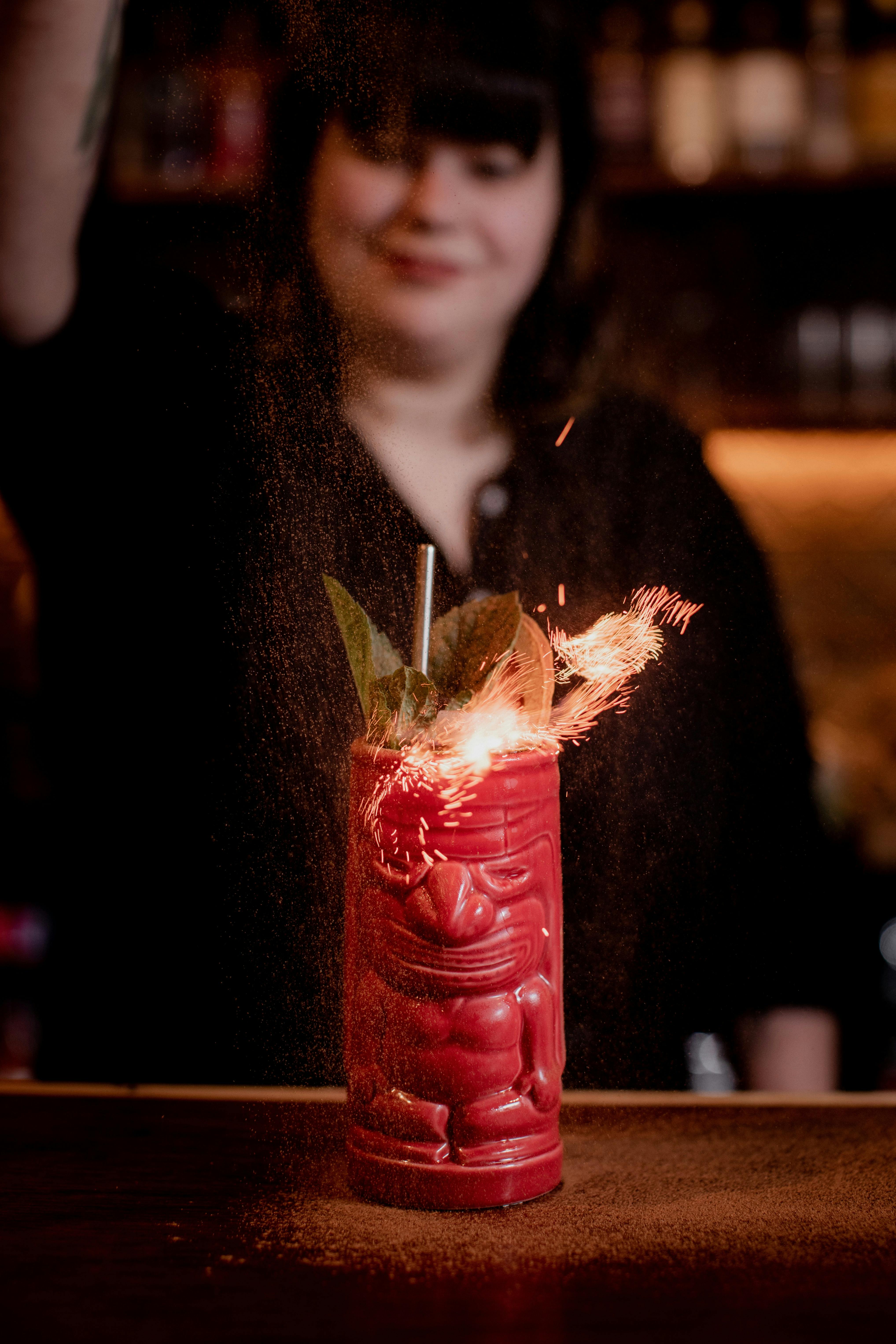 tiki cocktail in a red tiki mug that is on fire