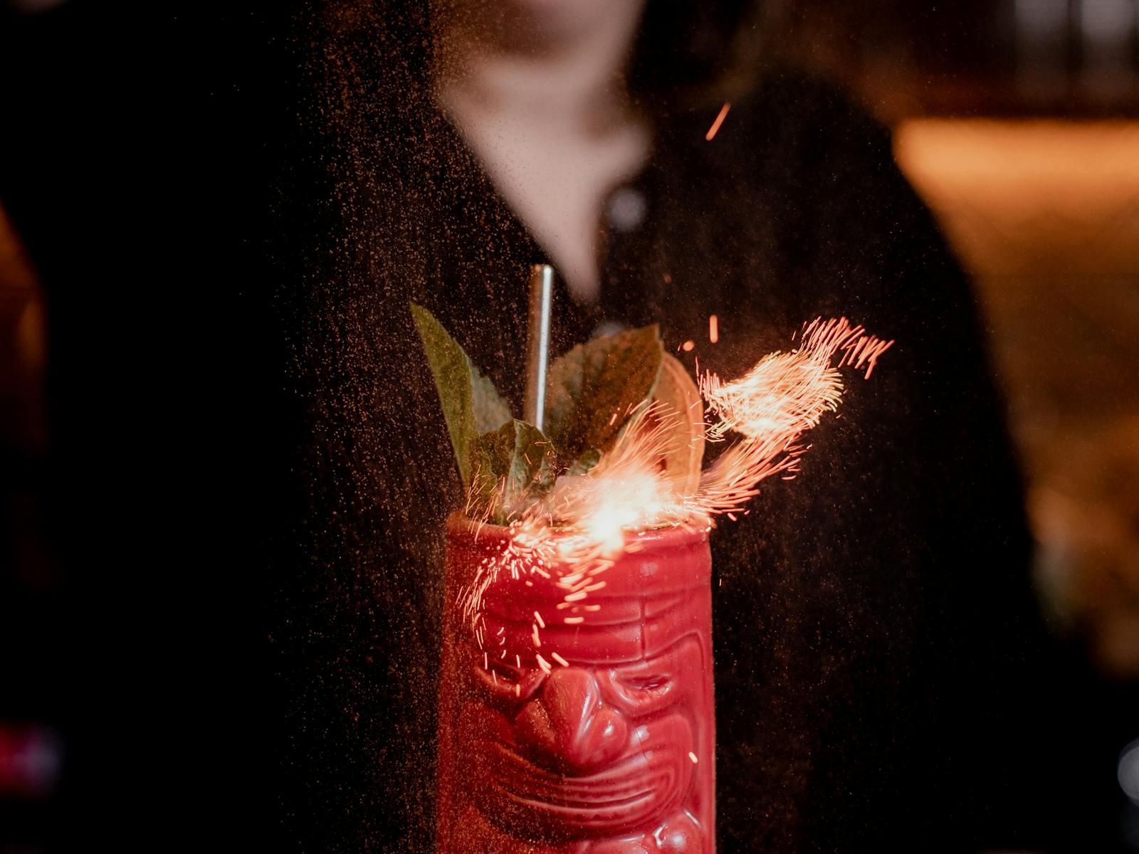 tiki cocktail in a red tiki mug that is on fire