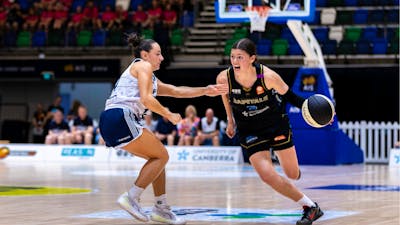 UC Capitals player driving to the basket for a layup during a WNBL game.