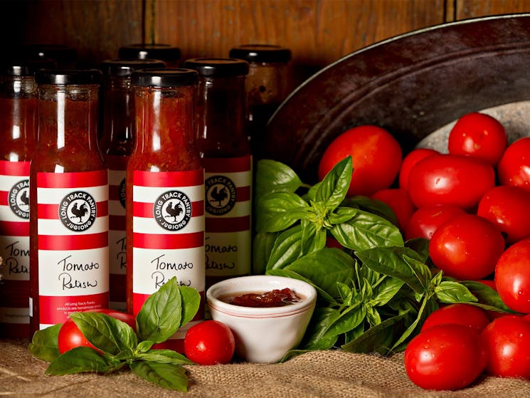 Jars of homemade relishes with fresh tomatoes and basil