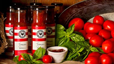Jars of homemade relishes with fresh tomatoes and basil