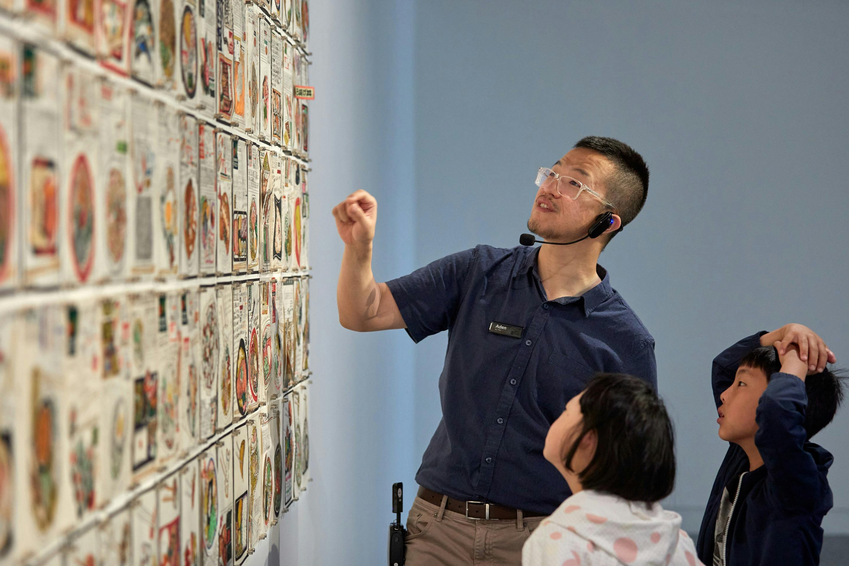 Male guide shows children an artwork as part of a gallery tour