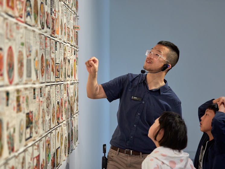 Male guide shows children an artwork as part of a gallery tour