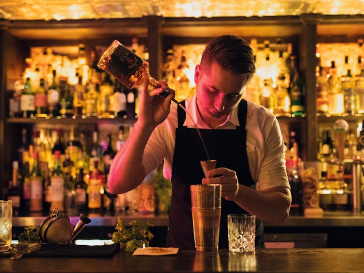 Bartender creating a cocktail at The Doss House bar in The Rocks