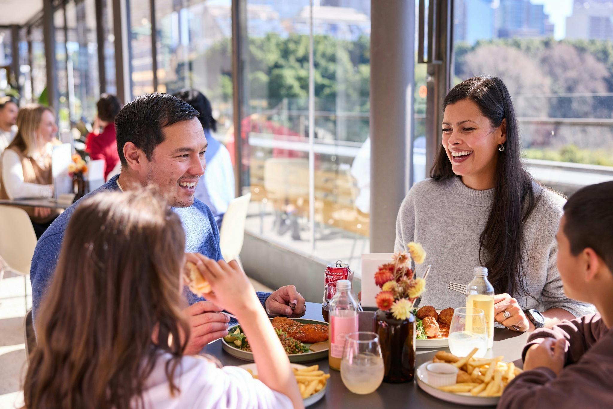 A family enjoys lunch at a table with views of Sydney CBD.