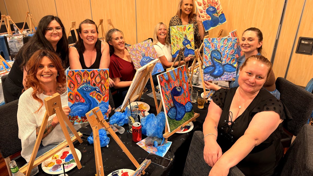 Paint Juicy guests painting at a table of canvases and palettes during a mobile paint and sip sessio