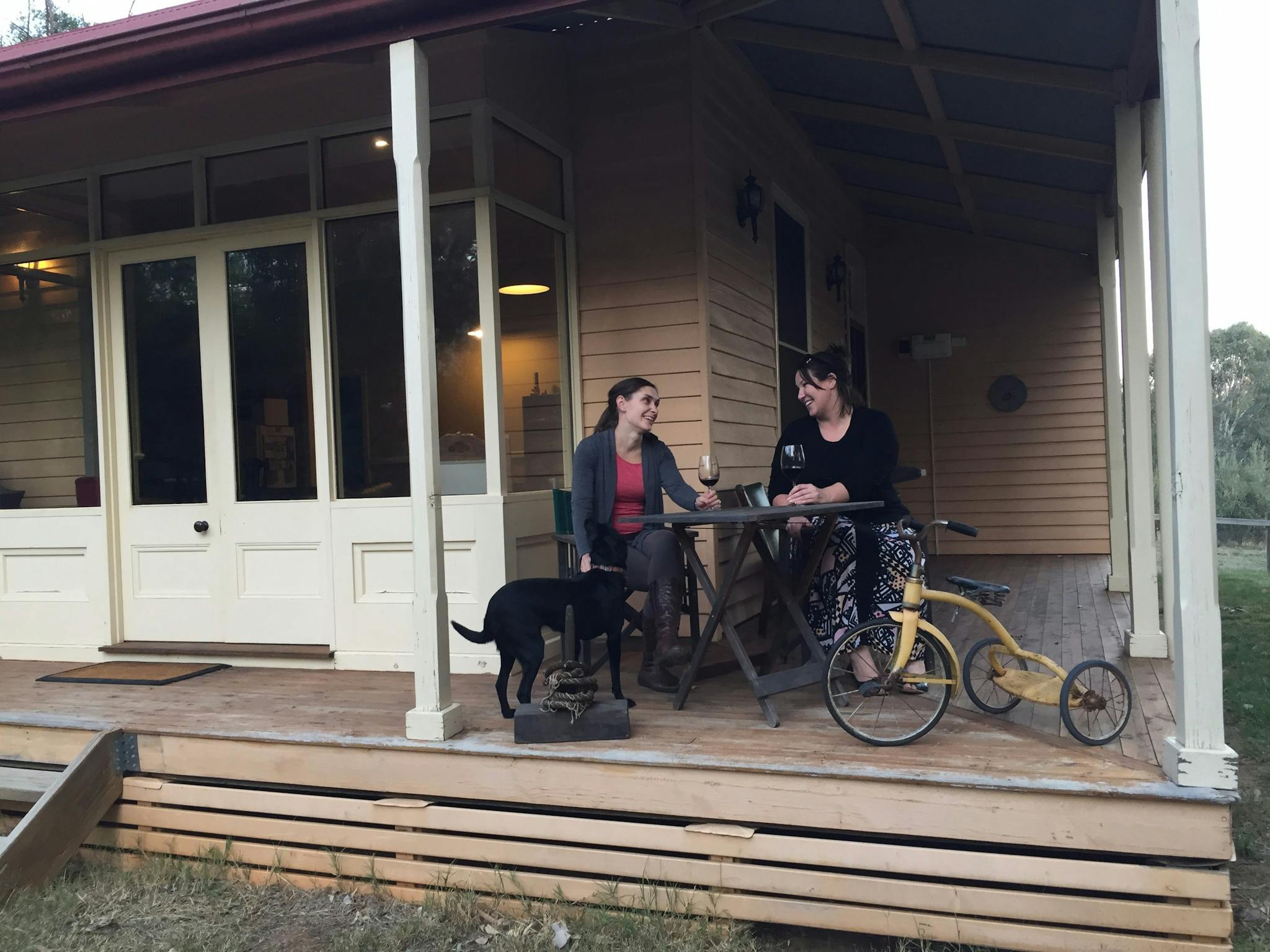 Ladies enjoying a wine on the Lottie's Cottage verandah with Mosey the dog
