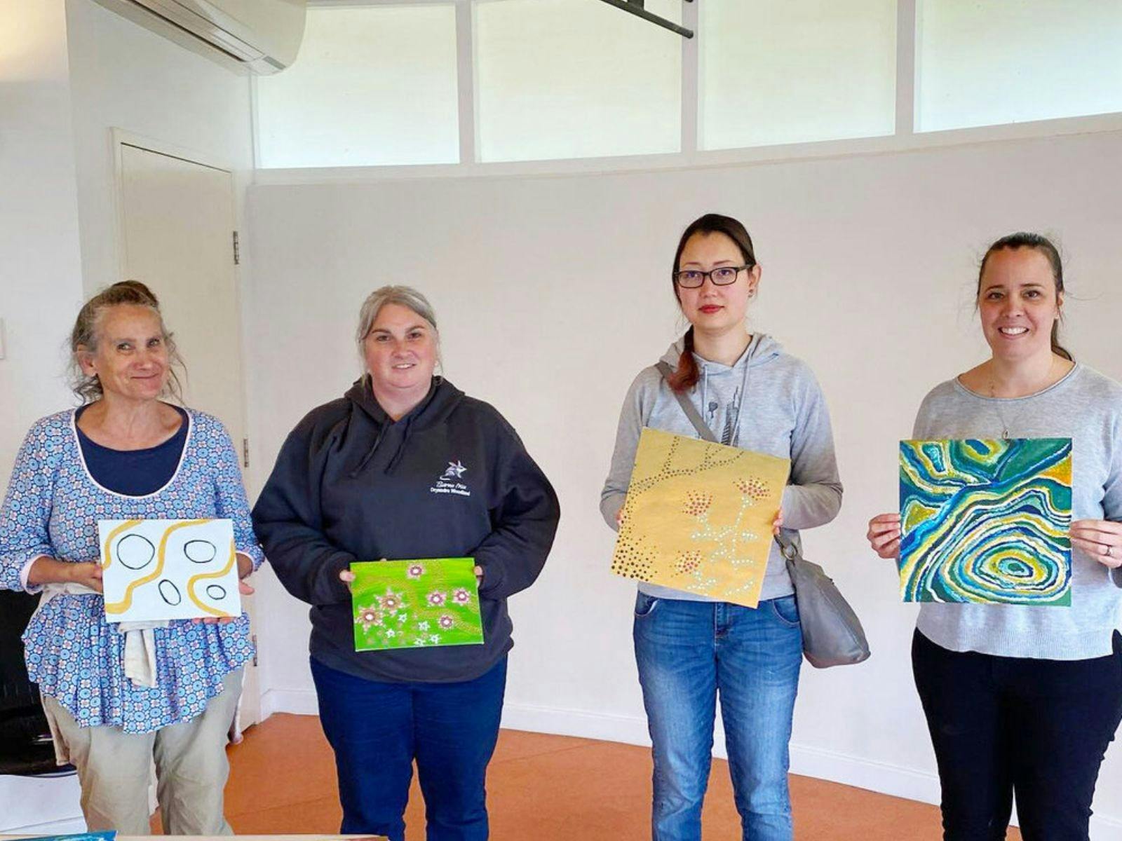 4 women showing off their dot paintings.