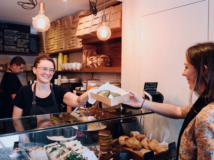 Woman purchasing baked goods at Flour and Stone bakery on Riley Street, Woolloomooloo