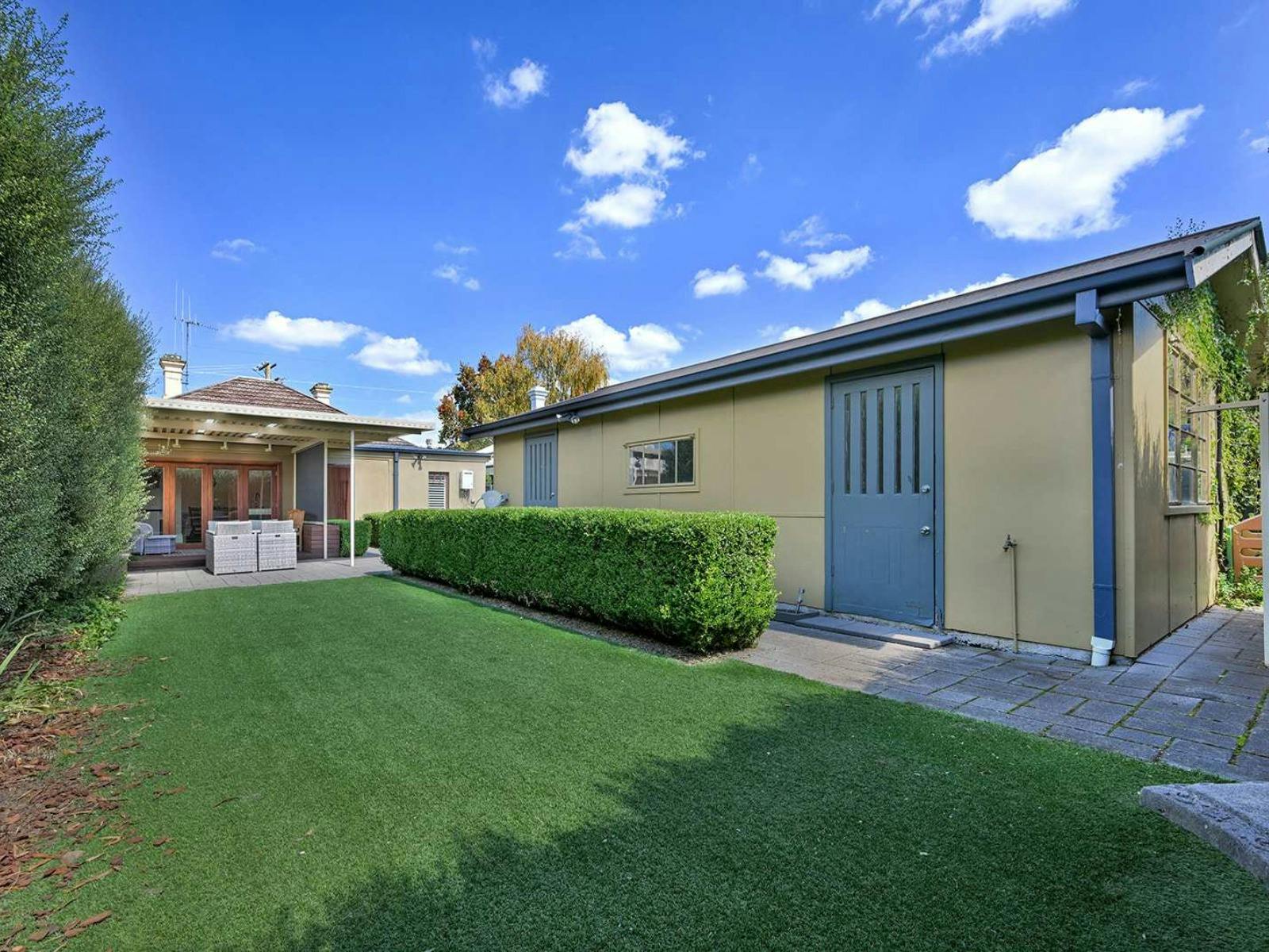Backyard with grass, shed, hedges