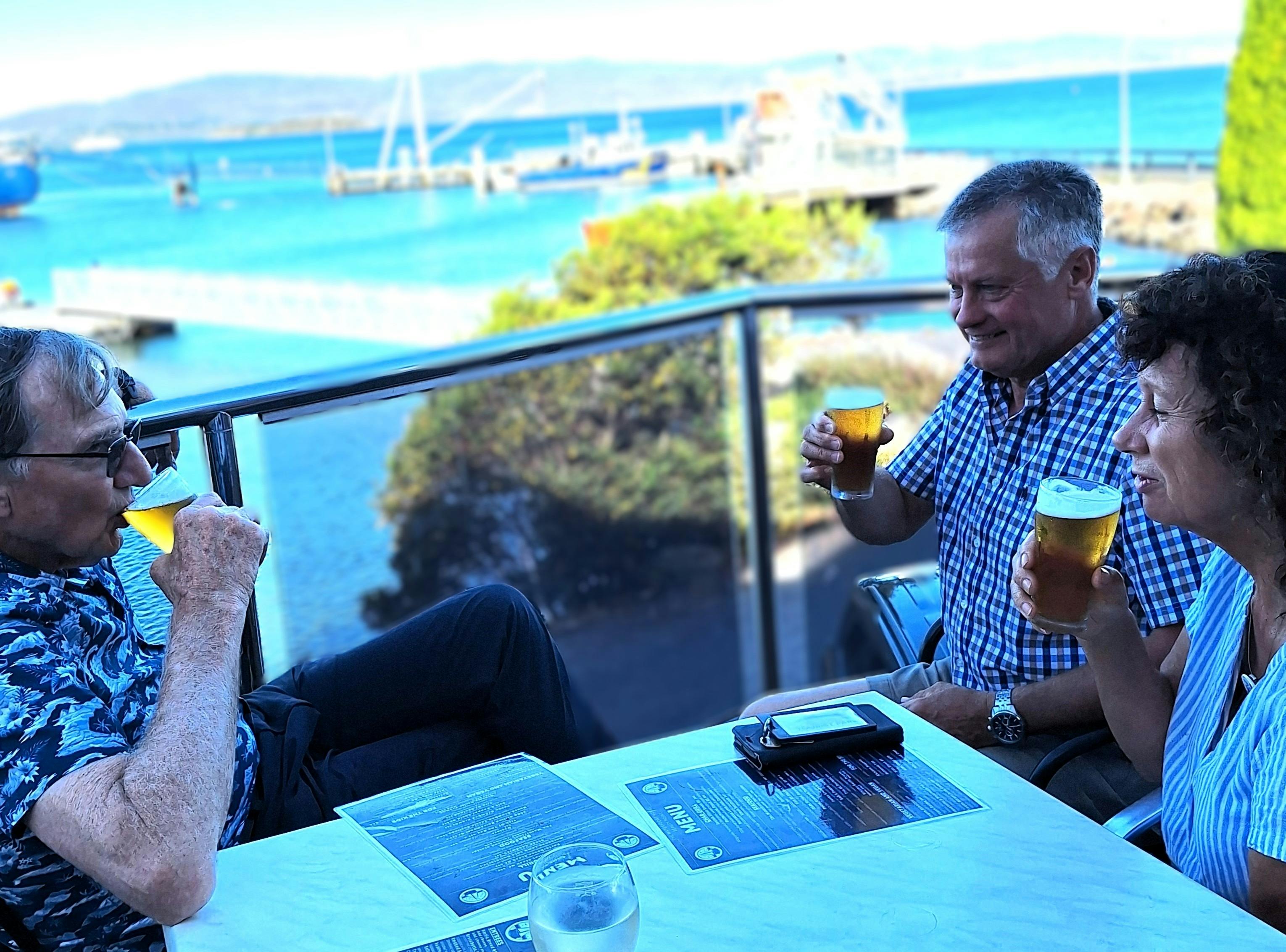 Three people dining on waterfront drinking beer