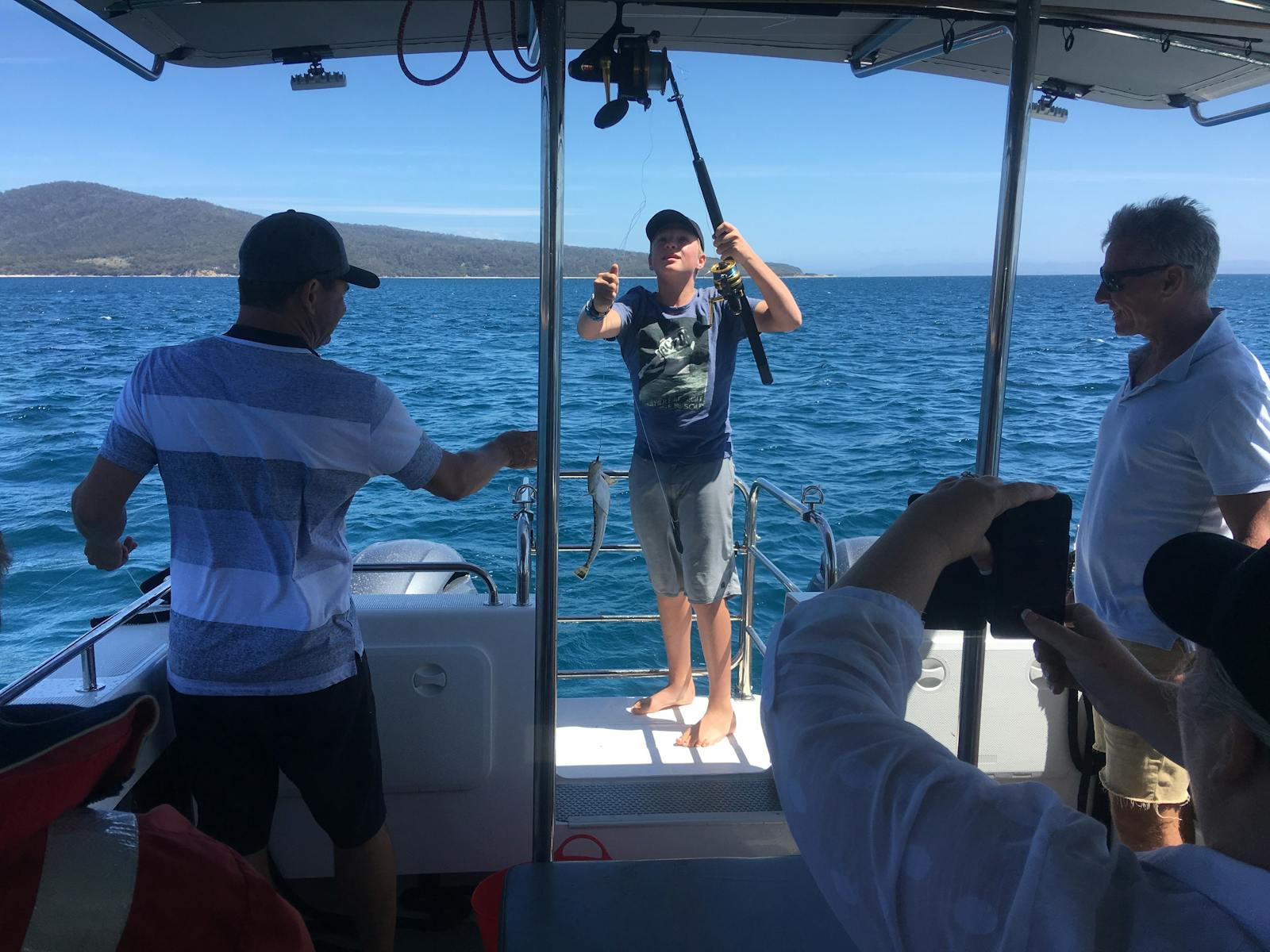 Shows guests with fishing rods, catching a fish from the back of the vessel