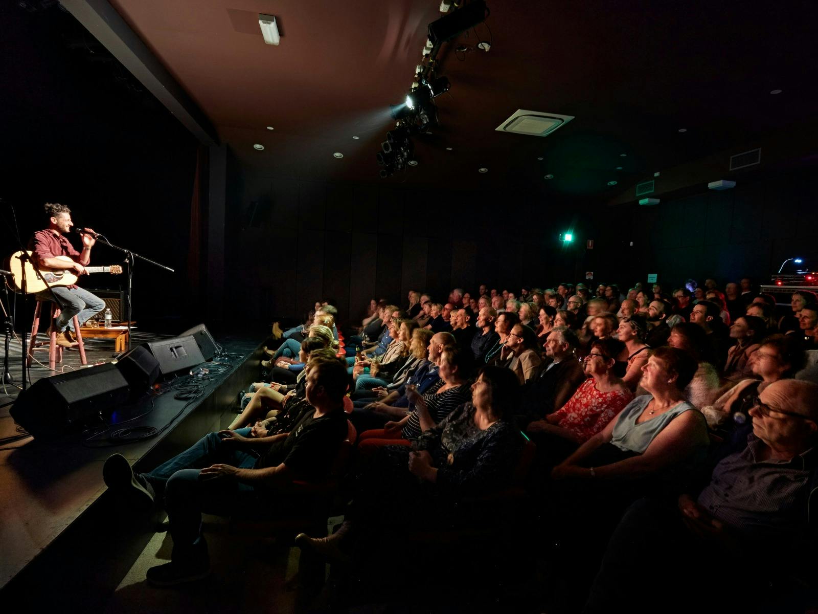 A full auditorium of patrons watching Lior on stage