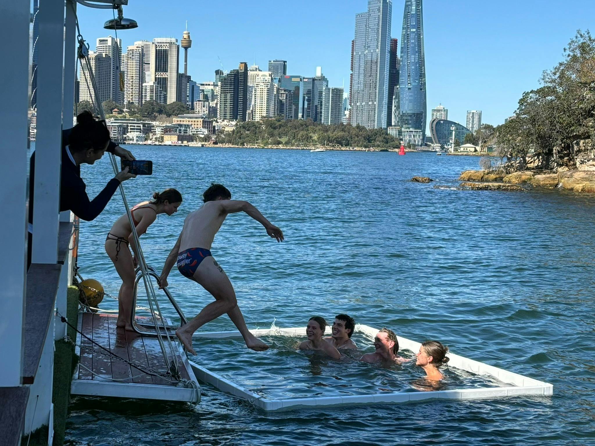 人们跳进港口水面上的围栏