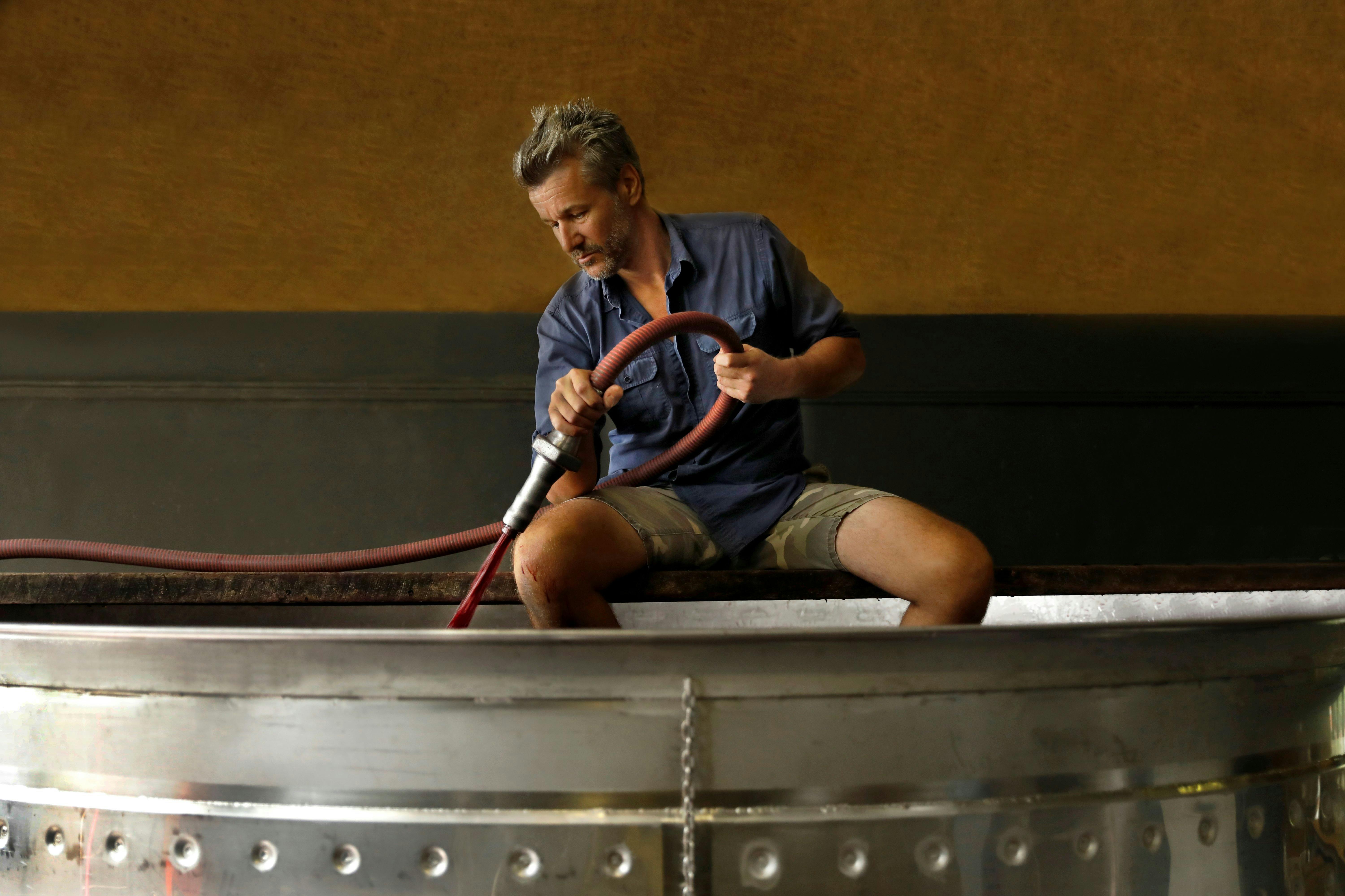 Winemaker Alex Woods pumping red grape juice into an open fermenter.