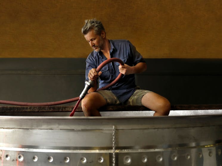 Winemaker Alex Woods pumping red grape juice into an open fermenter.