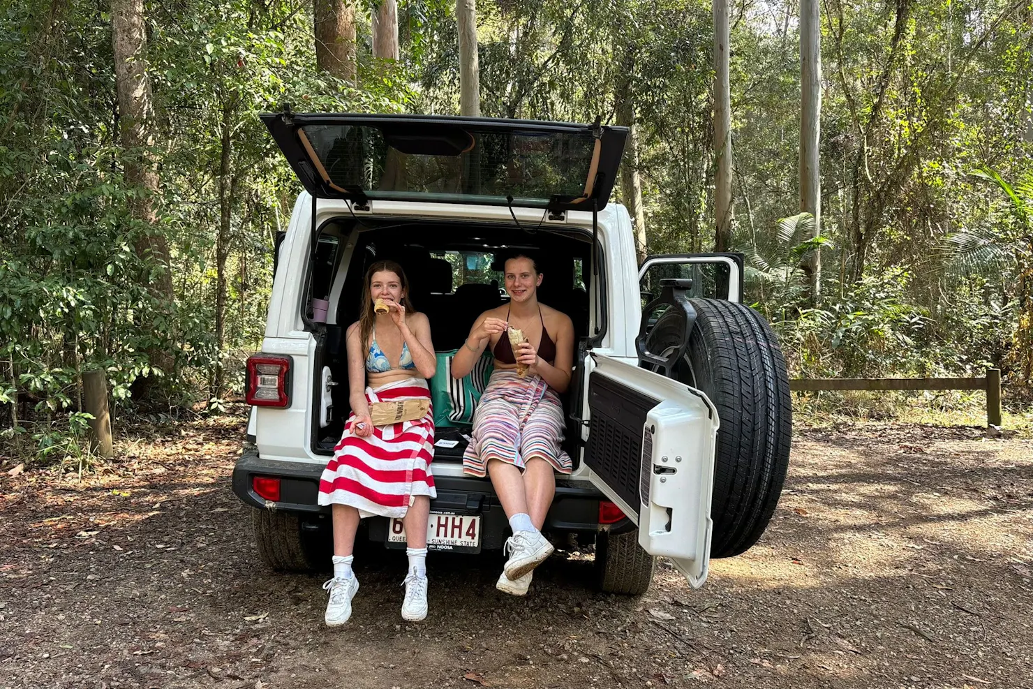 Sunny Jeeps, two girls sitting in the back of the Jeep enjoying light refreshments in nature