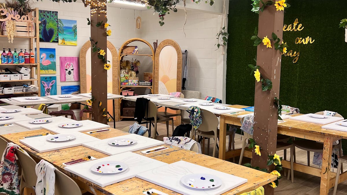 A beautiful setting of art tables with paint palettes and paint on tables ready for the start class