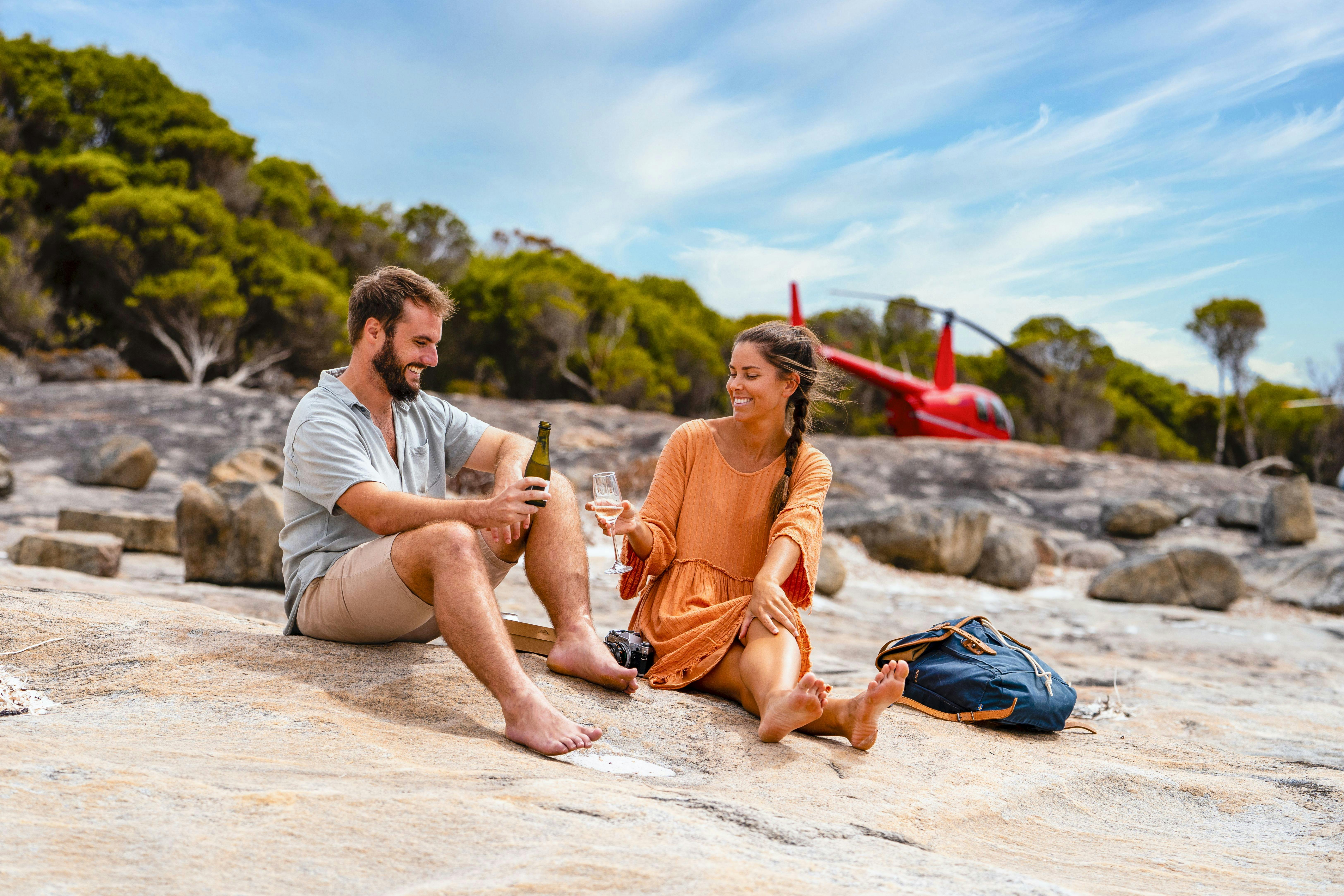 Couple enjoying beach picnic with helicopter in background