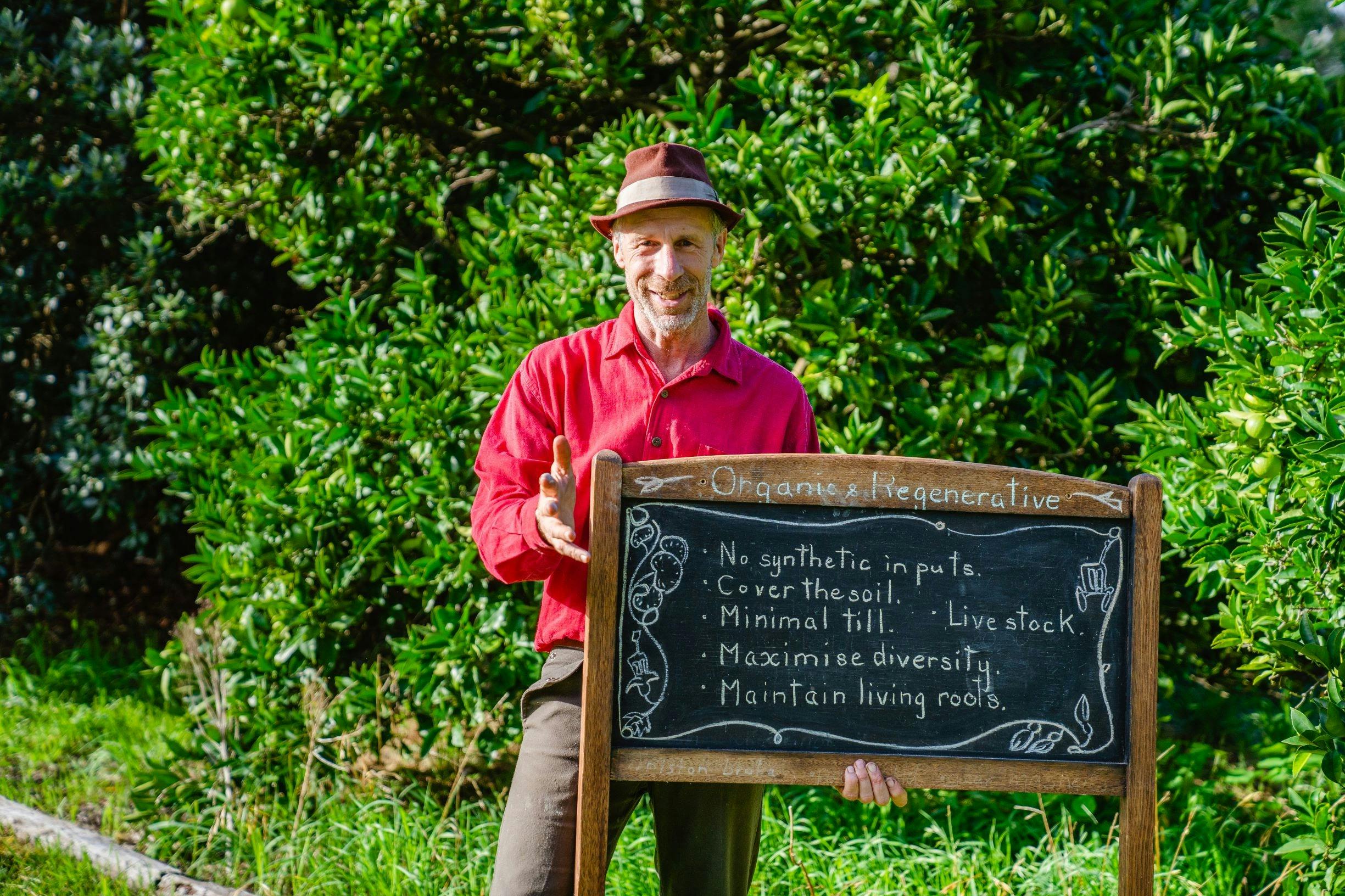 A man holding a blackboard highlighting the principles of Regenerative Agriculturewith th