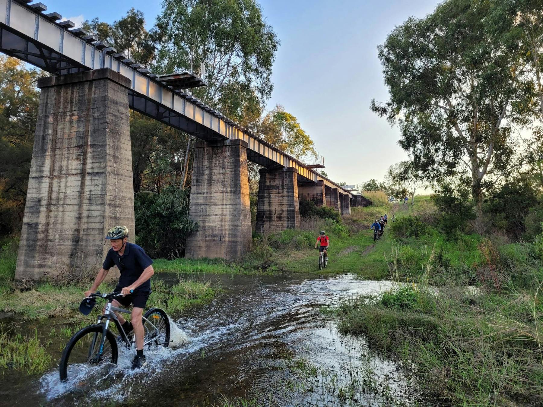 Riders going through water in the gully at the Golembil Bridge