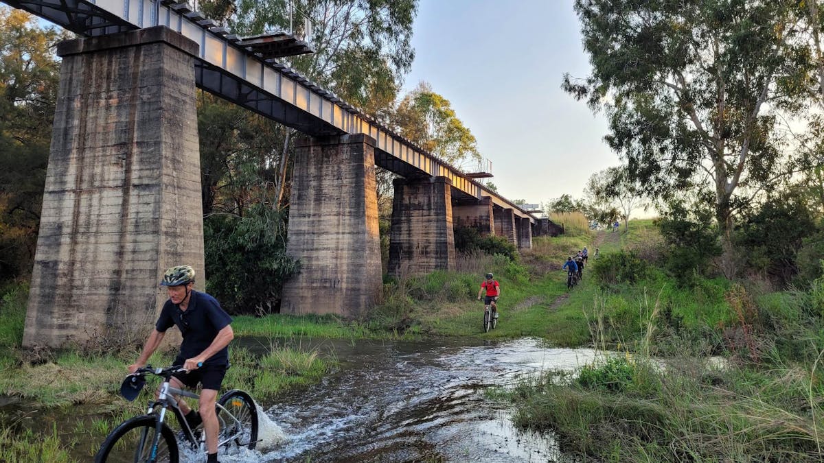 Riders going through water in the gully at the Golembil Bridge